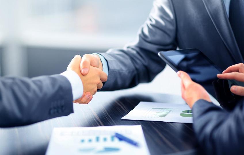Two businessmen shake hands over a table during a business meeting
