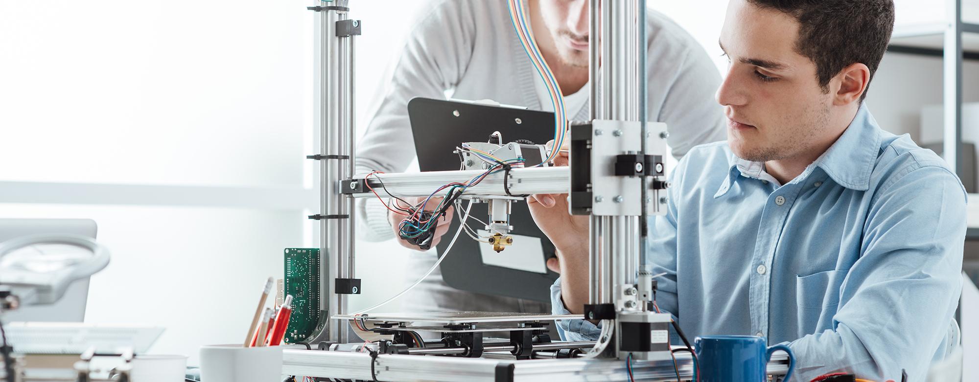 Two men working on a 3D printer