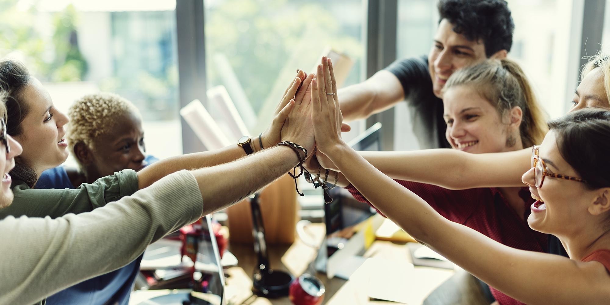 A group of people in an office with their hands in the air