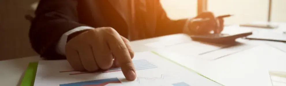 Businessman in suit pointing graphics on clipboard.