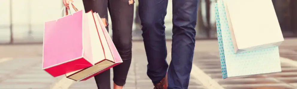 A man and a woman walking with shopping bags.