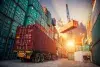 A truck is parked in front of a pile of containers.