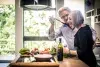 An elderly couple prepares food in the kitchen.
