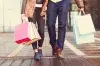 A man and a woman walking with shopping bags.
