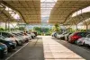 Cars parked under a shelter in a parking lot.