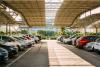 Cars parked under a shelter in a parking lot.